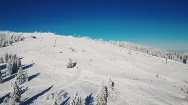 Kayak merkezi Feldberg, Schwarzwald, Almanya dondurucu güneşli kış gününde. Kayak merkezinde kayak ve snowboard yapan insanlar. Turistler ve sporcular kayak merkezindeki kırmızı ve mavi çizgilerde tepetaklak gidiyorlar. Kış sporu