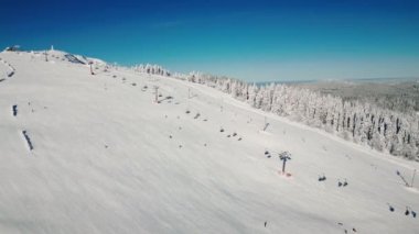 Almanya, Schwarzwald 'daki Feldberg kayak merkezinde kış sporları. İnsanlar kış güneşli bir günde tepelerde kayak ve snowboard yapıyor. Kış turizmi kavramı. Kayak pistleri ve tepeler