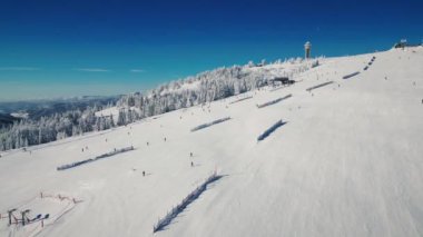Kış mevsiminde Schwarzwald, Almanya 'da karla kaplı hava manzarası. Güneşli dondurucu günde kayak pisti ve kayak asansörleri olan Feldberg kayak merkezi. İnsanlar yokuş aşağı kayıyor. Kış sporları