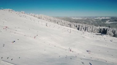 Almanya 'nın Feldberg kayak merkezinde kayak yapan insanlarla birlikte kayak pistleri ve kayak asansörleri. Kış sahnesinde kayak yapan aktif insanlar ve kış güneşli bir günde kayak yapan snowboardlar. Kış sporları