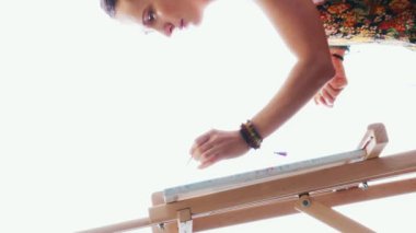 Kadın ressam evde akrilik boya kullanarak tuvale resim yapıyor. Genç utangaç kız fırça kullanarak resim çiziyor. İlham. Sanat akademisi ya da çizim okulu. Dikey video