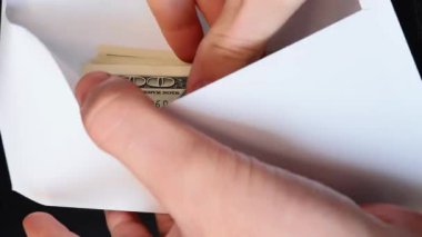 Eller nakit para banknotlarıyla beyaz zarfı açıyor. Yüz Amerikan Doları 'ndan oluşan yığınla banknot sayan kişi, yaklaşsın. Maaşını zarf içinde alan adam. Başarı kavramı. Dikey video