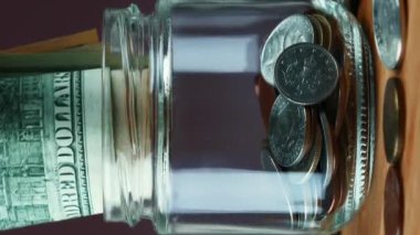 100 dolarlık banknotları cam kavanoz para kutusuna koyduk. Para tasarrufu konsepti. Finansal ve ekonomik konsept. Ekonomik büyüme kavramı. Dikey video