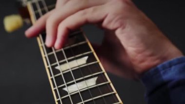 Erkek gitar çalışıyor. Gitarist adam elektro gitarda öğreniyor, yeni akorlar çalıyor. Müzisyen telli çalgılarla yeni bir şarkı söylüyor. Gitarda çalan adam. Gitar dersleri. Dikey video