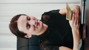 Kadın patronun elinde yığınla para var. İş kadını, ofis masasında el ele para tutuyor. İş yerinde çalışan kadın ofis çalışanı, para sayıyor. Finans ve iş dünyası. Dikey video.