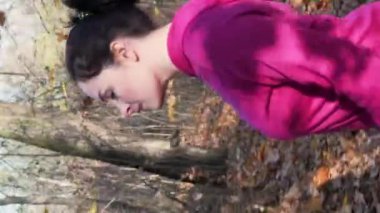 Sağlık konsepti. Sonbahar parkında İskandinav yürüyüşü. Dikey video. İskandinav yürüyüşü. Tombul, genç bir bayanı ormanda sırıklarla yürümeye motive etti. Kardiyo çalışması yapıyordu. Fitness aktivitesi. Kardiyo çalışması