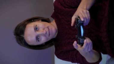 Kablosuz joystick kullanan, TV karşısında video oyunu oynayan bir kadın. Denetleyiciyle online oyun oynayan kız. Dikey video