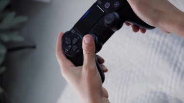 Eller video oyununda joystick kullanır. Kablosuz kontrolörle video oyunu oynayan, kontrol düğmelerine basan bir kadın. Dikey video