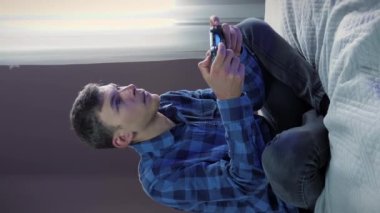 Oyun konsolunda oyun oynayan adam joystick kullanıyor. Erkek TV 'de online oyunlar oynuyor, kablosuz kumanda kullanıyor. Dikey video