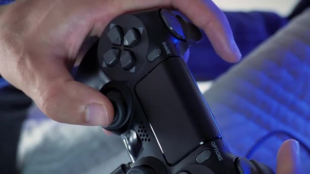 stock video Male hands holding joystick, pressing and pushing buttons, playing video game, close up. Hands play with wireless controller. Vertical video