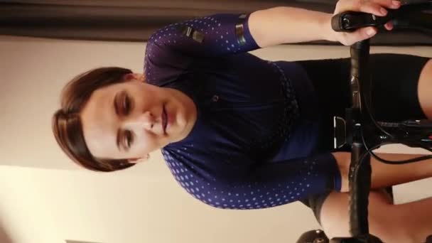 Kobieta Jeździ Rowerze Rowerze Treningowym Ćwiczy Cardio Pije Wodę Patrzy — Wideo stockowe