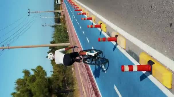 シティロード沿いのサイクルレーンパスで自転車に乗る男 後ろのショット 夏季にはアウトドアでの男性アスリートトレーニング バーティカルビデオ — ストック動画