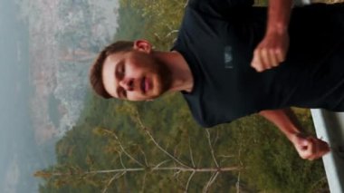 Koşu konsepti. Açık havada koşan bir adamın portresi, dağ yolunda inanılmaz bir manzarayla egzersiz yapıyor. Dikey video