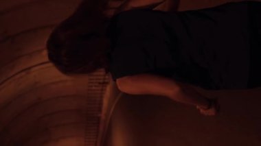 Tünelde bir kadın koşucu. Kadın boş tünel boyunca koşuyor. Kadın triatlet dışarıda antrenman yapıyor. Dikey video