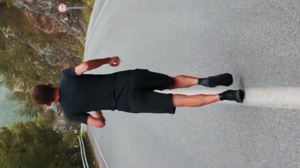 山でジョギングする男 アウトドアを実行するトライアスリート 耐久トレーニングを行います バーティカルビデオ — ストック動画