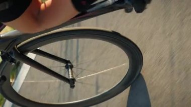Bisikletli bacaklar gün batımında bisiklete pedal çeviriyor, bisiklet tekerleği ve zincir dönüyor. Gün batımında bisiklet süren bir bisikletçi. Bisiklet ve sürüş sistemi dönüyor. Dikey video
