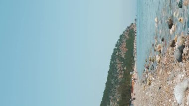 Güzel deniz manzarası. Güneşli bir günde deniz kıyısında sakin bir su. Deniz sakin dalgaları kumsala ulaşıyor ve çarpıyor. Dikey video