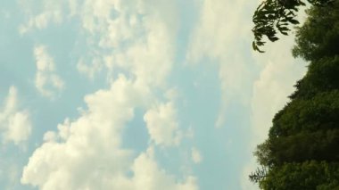 Açık mavi gökyüzüne karşı hızlı hareket eden bulutların zaman akışı. Kabarık bulutların dikey videosu