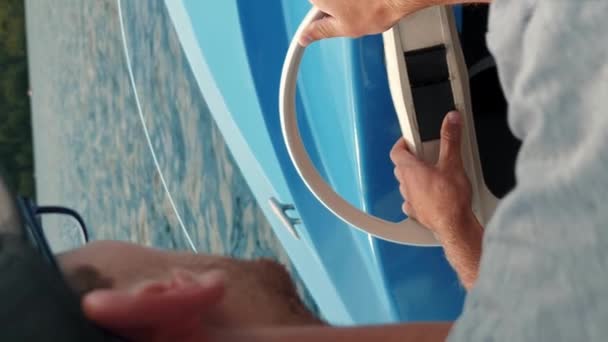 観光客の電気ボートで車輪を回す男性の手の近くで 湖に沿って運転 船に浮かぶ男が水に浮かんでいる バーティカルビデオ — ストック動画