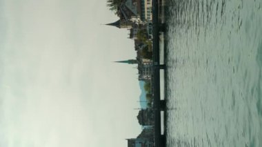 Köprüsü olan bir nehir kıyısı ve Zürih 'in eski merkezinde eski bir kilise kulesi. İsviçre 'nin Zürih şehrinin ünlü eski turist merkezi. Dikey video