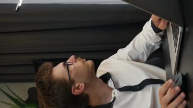 Adam dizüstü bilgisayarı kapatıyor ve akşam çalışma masasında işini bitiriyor. Gözlüklü bir iş adamı ofisteki defterini bitirir. Dikey video