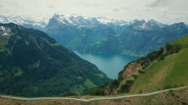 Lucerne Gölü 'nün arka planında turkuaz berrak su ve karlı kayalık dağlar var. Dağlar ve tepelerle çevrili İsviçre 'deki göl manzarası.