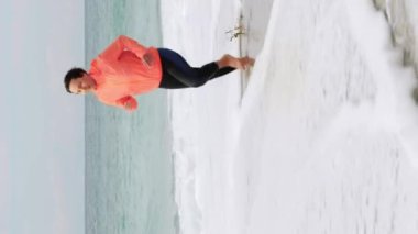 Deniz kıyısında koşan motive edici atletik kadın. Genç sportif bayan, kumlu sahilde koşuyor, spor egzersizleri yapıyor. Çalışan kavram. Dikey video
