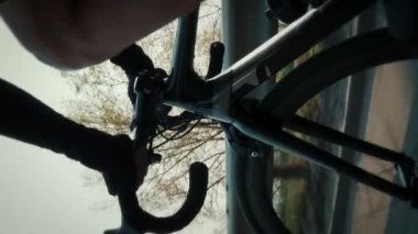 Bisiklet gidonunu vites kolları ve ön bisiklet tekerleği ile kapatın. Bisikletçi bisikletle şekil değiştiriyor. Dikey video