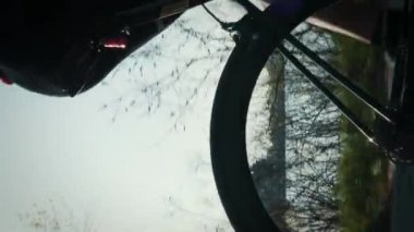Gün batımında bisiklet tekeri dönüyor. Erkek bacakları parkta pedal çeviriyor, bisiklet teçhizatını kapatıyor. Bisikletçi gün batımında bisiklet yolunda pedal çeviriyor. Dikey video