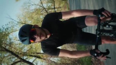 Atletik formda bir bisikletçi Green Park 'ta bisiklet sürüyor. Profesyonel bisikletçi bisiklet eğitimi alıyor. Spor erkeği bisiklet yolunda ilerliyor. Dikey video