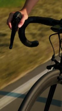 Yol bisikleti gidonunu GPS navigatörüyle kapat. Bisikletçi bisikletle vites değiştiriyor, ellerinizi ve dişlilerinizi güneş ışığında kapatıyorsunuz. Dikey video