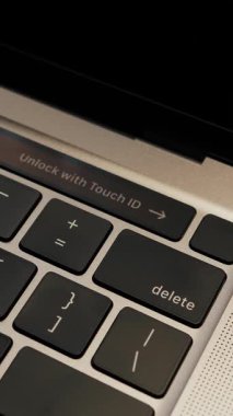 Man unlocking laptop computer with touch ID close up of laptop keyboard. Fingerprint sensor on computer, close up. Vertical video