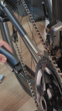 Man is lubricating road bike chain with white lube. Bicycle mechanic lubricating chain of bicycle in bike workshop. Repairing bike. Bike maintenance. Vertical video