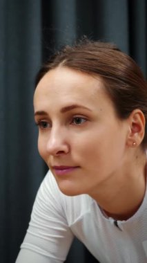Portrait of female cycling on smart bicycle trainer at home. Woman cyclist is doing cardio exercises on indoor stationary trainer. Bike exercises. Indoor cycling. Vertical video