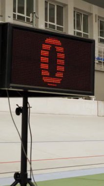 Close up of electronic board with lap numbers on velodrome. Bike race on cycling track. Cyclist racing on velodrome, riding fixed gear bicycle. Vertical video