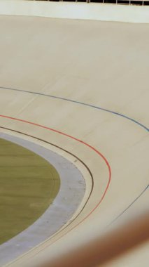 Professional cycling teams racing on open velodrome. Cycling track. Cyclists riding bicycles with fixed gear on high speed in curve. Cyclists training on velodrome. Vertical video