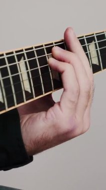 Elektro gitarla oynayan erkek eller, yakın çekim. Gitar panosundaki parmaklar akor çalıyor. Müzik aletleri konsepti. Dikey video