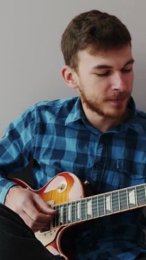 Sakallı ve mavi gömlekli gitarist elektro gitar çalar. Elektro gitar çalan çekici erkek müzisyen, yeni akorlar çalıyor. Müzik konsepti. Dikey video