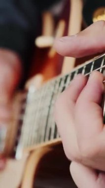 Elektro gitarla oynayan erkek eller, yakın çekim. Gitar panosundaki parmaklar akor ve solo çalıyor. Müzik aletleri konsepti. Dikey video