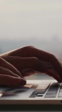 Dizüstü bilgisayarın klavyesinde ofisteki pencereye karşı dokunmatik dokunmatik dokunmatik yazı yazan kadın elleri. İş konsepti. Dikey video