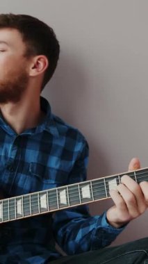 Elektro gitarda solo çalan sakallı erkek müzisyen portresi. Eller elektro gitarda rock 'n roll konseri için pratik yapıyor. Dikey video