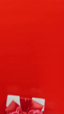 Kadınlar Sevgililer Günü 'nde, Noel' de ya da doğum gününde erkeklere hediye paketi verir. Hediyeyi kapat. Kırmızı arka planda kırmızı kurdeleli beyaz hediye kutusu görünüyor. Tatil hediyesi. Dikey video