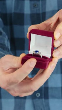 Elleri evlilik teklifi için evlilik yüzüğünü kutuda tutuyor. Adam alyansla kırmızı kutuyu tutuyor ve açıyor. Sevgililer Günü hediyesi ya da nişan, kapat. Dikey video