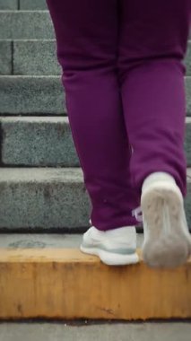 Kışın şehir parkında merdivenlerden yukarı çıkan beyaz spor ayakkabılı kadın bacaklarını kapatın. Sportif kadın kardiyo fitness egzersizleri yapıyor. Aktif yaşam tarzı. Dikey video