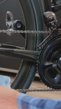 Mavi mikrofiber bezle bisiklet zincirini temizliyorum. Düzenli bisiklet bakımı. Tamirci bisiklet atölyesinde bisiklet zincirini bezle temizliyor. Dikey video