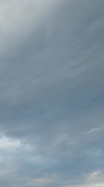 Bulutlar. Zaman, beyaz bulutları aşıyor. Mavi gökyüzünde hızlı hareket eden bulutlar. Bulutlar hareket ediyor. İnanılmaz fırtınalı bir gökyüzü. Güzel doğa manzarası. Dikey video