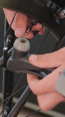 Bisiklet lastiği lastiğine hava pompalamadan önce bisiklet teknisyeninin bükülmemiş kapağı. Bisiklet tamiri. Bisiklet tamirhanesi. Dikey video