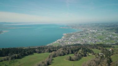 Güneşli bir günde Avusturya, Bregenz 'deki Constance Gölü ve karlı dağların panoramik drone görüntüsü. Resimli doğa manzarası