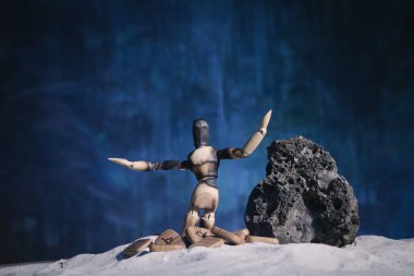 Elleri ıssız bir arazide olan ahşap insan figürü. Umutsuzluğun sembolü ve 