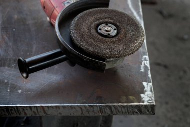Kalın metal bir plakanın üzerinde duran bir üçgen öğütücüye kaynak yapmak için bir disk..